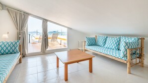 Une pièce avec un canapé, une table et une vue sur la mer.