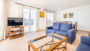 En stue med sofa, fjernsyn og spiseplads med stole og bord.