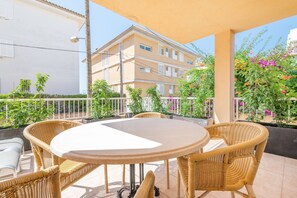A covered outdoor patio with wicker furniture and a round table.