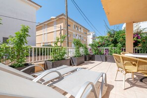 A balcony with lounge chairs, a table, and potted plants.