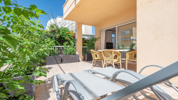 En balkon med loungesenge, et bord og plantekasser.