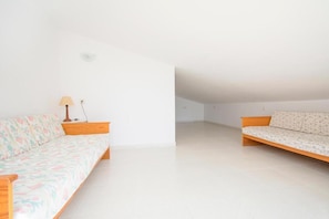 A room with two sofas, a lamp, and a white tiled floor.