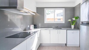 Eine moderne Küche mit weißen Schränken, einem eingebauten Herd, einem Fenster und einem Geschirrspüler.