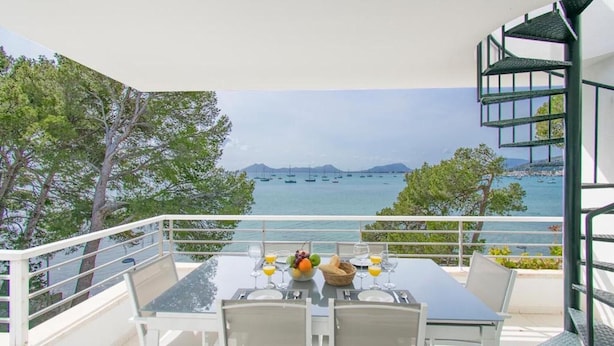 Ein Tisch mit Stühlen auf einem Balkon mit Blick auf ein Gewässer und Boote.