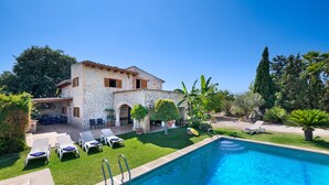 A stone villa with a swimming pool, outdoor seating, and lush greenery. - Pet-friendly Villa Cala Veritat with Mountain View, Pool, A/C, Wi-Fi, Garden, Terrace & Balcony (inca)