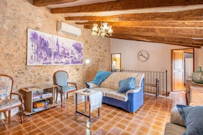 Una sala de estar rústica con vigas de madera a la vista, un sofá, sillones, una mesa de centro y obras de arte en la pared.
