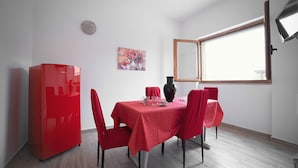 Comedor con una mesa dispuesta para cuatro, un refrigerador rojo y una ventana con vistas.