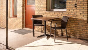 A brick building with a wooden door, a window, and a table with two chairs.