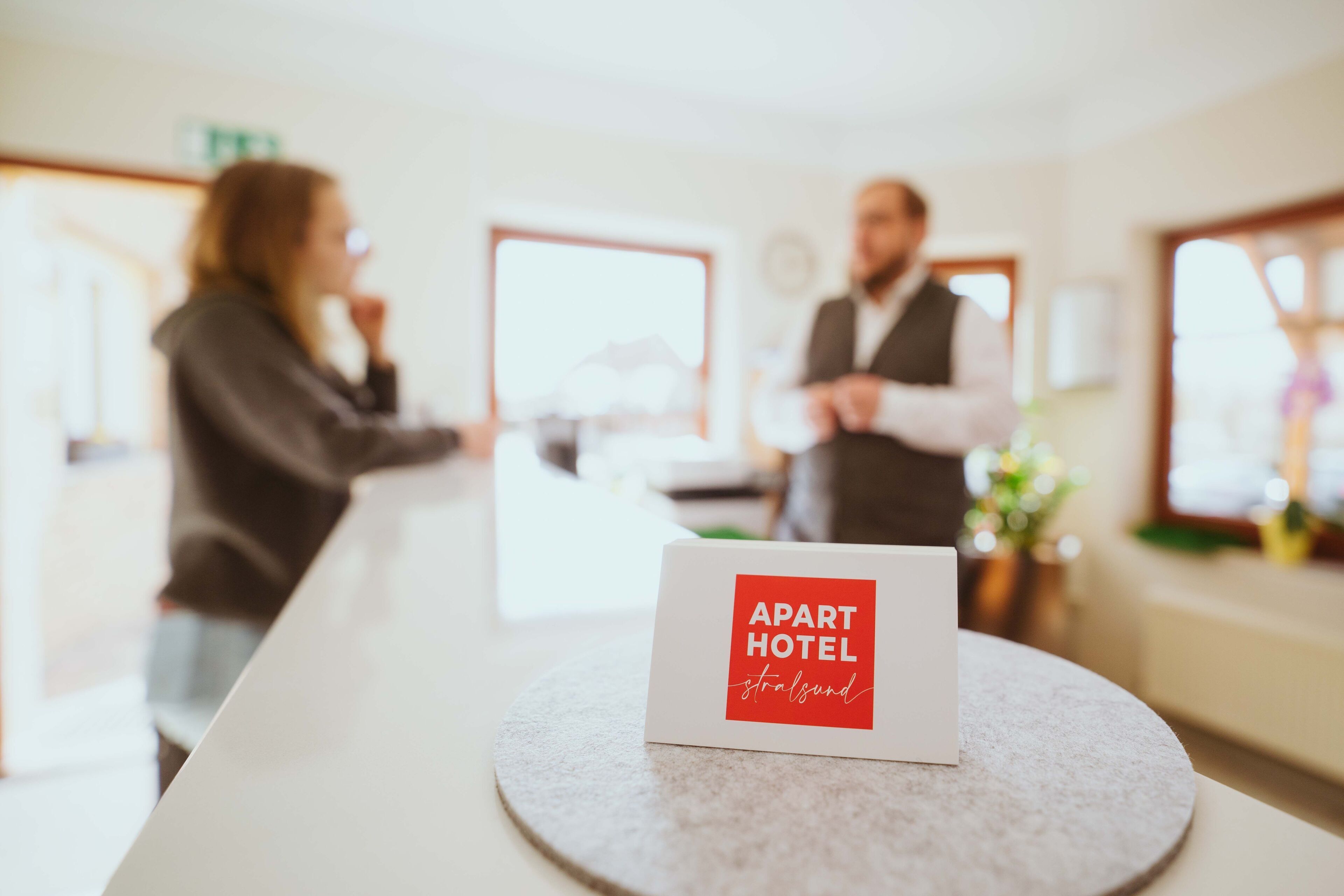 Una recepción con un cartel que dice 'APART HOTEL' y un hombre y una mujer al fondo.