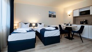 A hotel room with two beds, a dining table, chairs, a microwave, and a coffee maker.