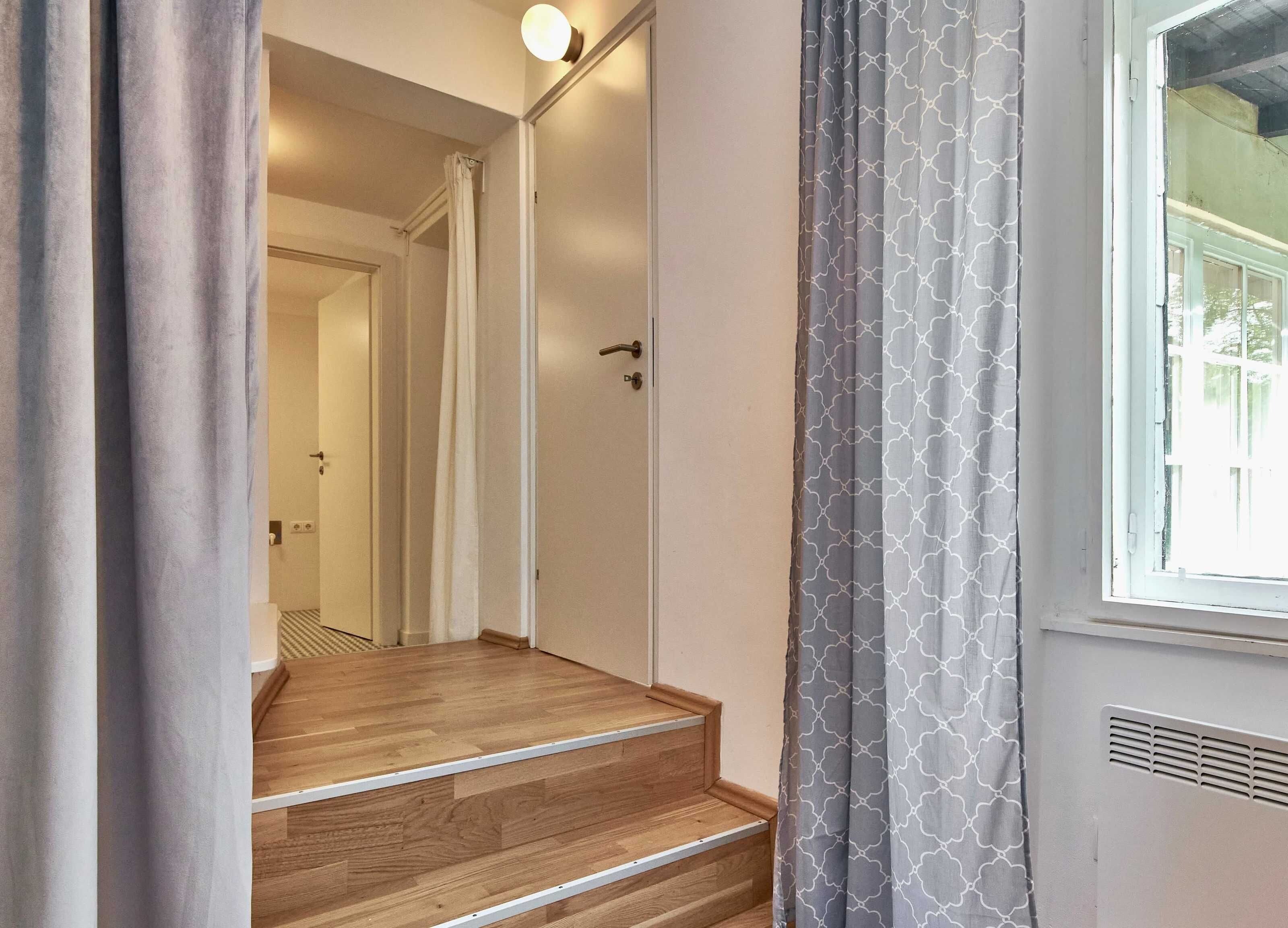 A staircase leading to a room with a window, a door, and a light fixture.