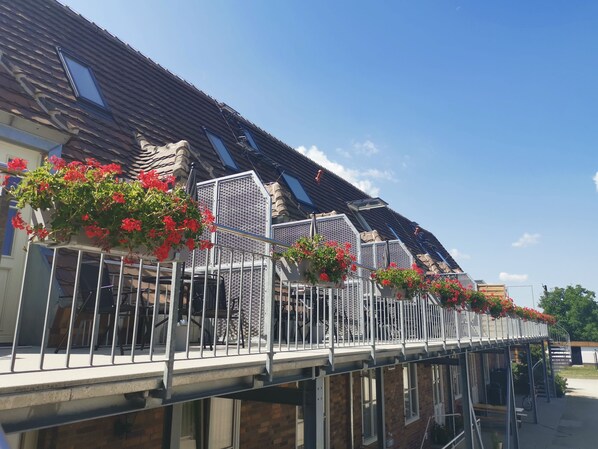 Un bâtiment doté d’un toit en pente, de nombreuses fenêtres et d’un balcon avec des garde-corps en métal.