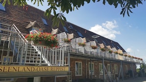 A building with a sign reading "SEENLAND-OASE REPPIST" and a staircase leading to a balcony with flower boxes. - Zimmer 3 - Seenland-oase Reppist (Senftenberg)
