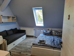 Un dormitorio compacto y moderno con cama estilo loft, una banca integrada y un tragaluz.