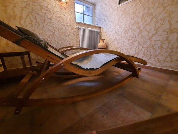 Een houten schommelstoel in een kamer met stenen muren en een radiator.