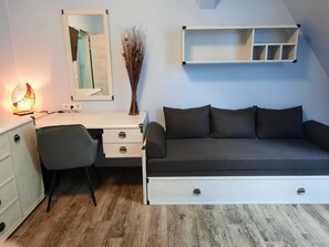 Une chambre moderne équipée d’un bureau, d’un canapé, d’un miroir et d’une étagère fixée au mur.