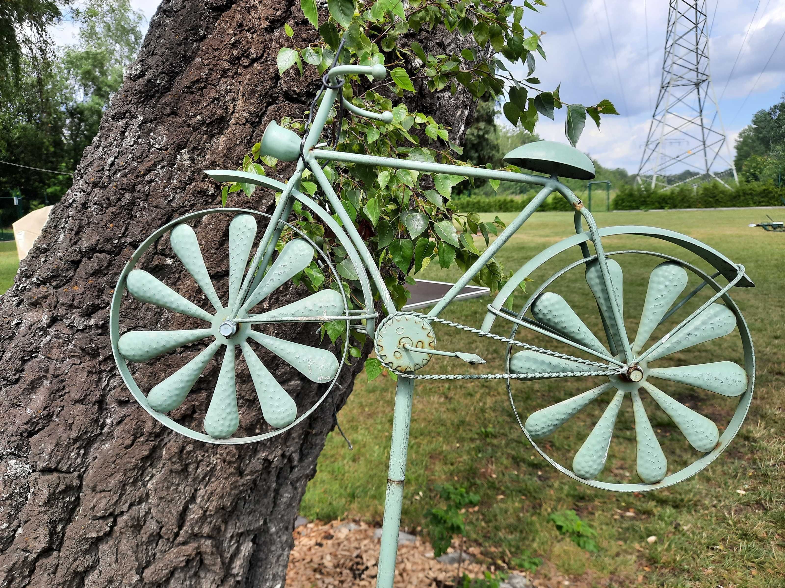 Ein altes Fahrrad an einem Pfahl befestigt, umgeben von viel Grün und einem Strommasten im Hintergrund.