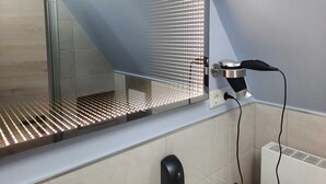 Een badkamer met een grote spiegel, een haardroger en ventilatie.