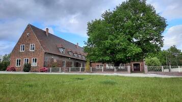 Een groot, bakstenen huis met een opvallende boom ervoor.