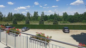 A parking area with cars, a metal railing, and greenery in the background. - Zimmer 3 - Seenland-oase Reppist (Senftenberg)