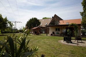 Un quartier résidentiel avec une maison dotée d’un toit en pente, d’un patio couvert et d’un barbecue.