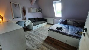 A bedroom with a bed, a desk, a chair, a radiator, and a window. - Zimmer 5 - Seenland-oase Reppist (Senftenberg)