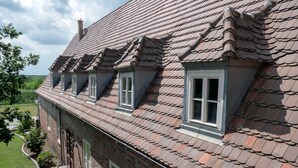Een tweelaags bakstenen gebouw met schuin dak en dakramen.