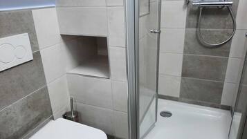 Un baño moderno con ducha de vidrio, inodoro y lavabo.