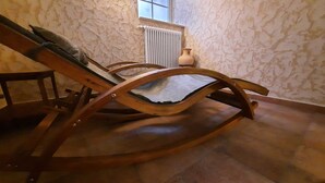Een houten schommelstoel in een kamer met stenen muren en een radiator.