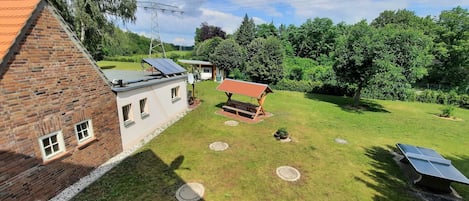 Una propiedad residencial con una casa de ladrillo, paneles solares, un banco de madera y un césped bien cuidado.