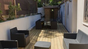 Un patio exterior con mobiliario de mimbre y una terraza de madera.