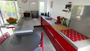 Una cocina moderna con una isla central, sillas rojas, una mesa de comedor y vistas al exterior.