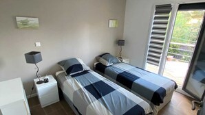 Un dormitorio con dos camas, un escritorio y una ventana con persianas.