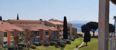 A coastal hotel with multiple buildings, a well-maintained lawn, and a clear view of the sea.