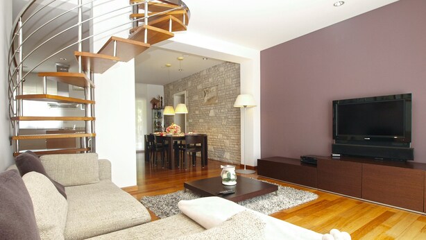 A modern living room with a spiral staircase, a flat-screen TV, a sofa, and a dining area with a stone wall. - Villa 2103/39323 (Istria - Pula), 2500m from the beach (Pula)
