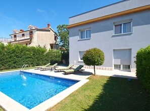 Ein modernes Gebäude mit Pool, Liegestühlen und einem gepflegten Rasen.
