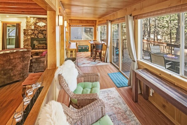 Un interior de madera con chimenea, una zona de estar y vistas al exterior.