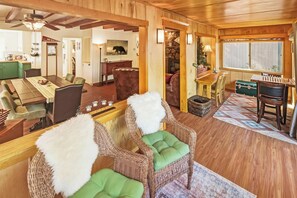 Een gezellig interieur van een blokhut met een eethoek, een open haard en een groot raam.