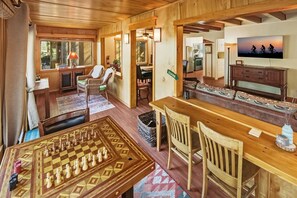 Un interior de madera con una mesa de ajedrez, sillas, un televisor y un comedor.