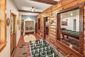 A cozy room with a foosball table, a wooden bench, and a canopy bed.