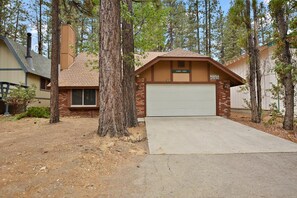 Une maison de plain-pied avec un garage, entourée d’arbres.