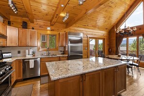 Une cuisine spacieuse dotée de meubles en bois, d’appareils électroménagers en acier inoxydable et d’un plan de travail en granit.