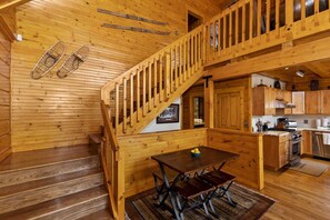 A wooden interior with a staircase, a dining area, and a kitchen. - Luxury Log Home with Mountain Views! Quiet Family Neighborhood! Gameroom! Firepit! (Big Bear City)