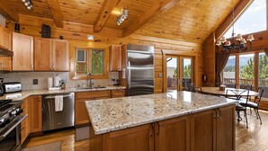 Une cuisine spacieuse dotée de meubles en bois, de plans de travail en granit, d’appareils électroménagers en acier inoxydable et d’un grand îlot central.