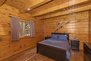Une chambre dans une cabane en bois, avec un lit, des tables de chevet et une fenêtre avec des rideaux.