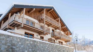 Un edificio de varios pisos con balcones, muros de piedra y un paisaje nevado.