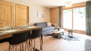 Una sala moderna con una mesa de comedor de madera, un sofá gris y una pequeña mesa redonda de centro.