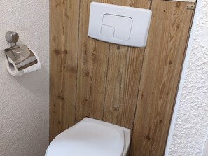 A bathroom with a wooden panel wall, a toilet, and a toilet paper holder. - Studio at the foot of the slopes for 4 people with large balcony (La Joue du Loup)