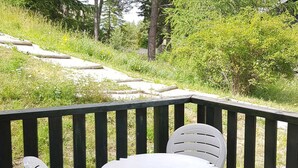 Una terraza de madera con una mesa blanca y dos sillas.