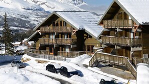 Un hotel de estilo chalé con balcones de madera, con vistas a una montaña nevada.